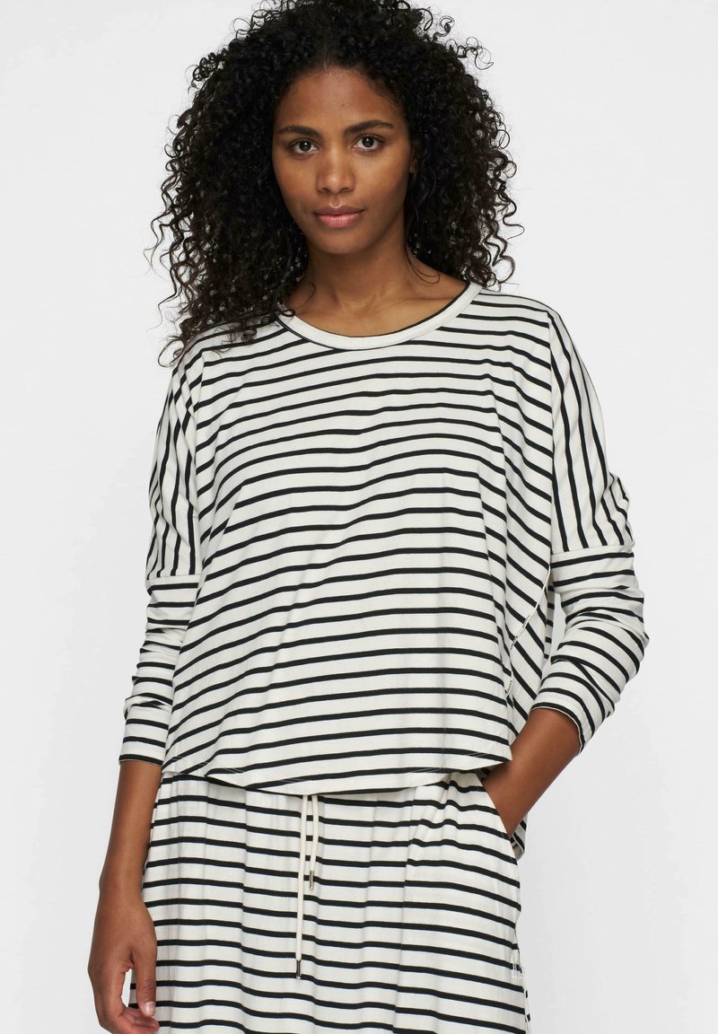 Top de manga larga a rayas y falda a juego en blanco roto y negro. Material suave, corte holgado, con un escote redondo y cinturilla ajustada.