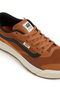 Bruna Vans-sneakers med ovandel i mesh, svarta accenter, en texturerad gummisula och en logotagg på tungan. Snörena matchar skons färg.