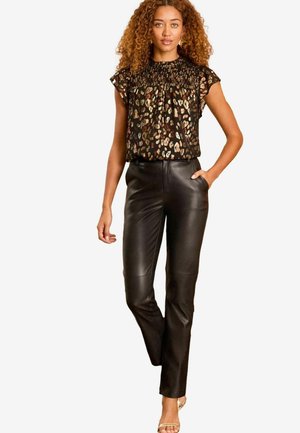 Pantaloni in pelle nera slim fit con tasche laterali, abbinati a un top nero con stampa leopardata multicolore e maniche a volant.