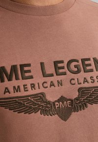 Roze sweatshirt met donker groene geborduurde tekst "PME LEGEND AMERICAN CLASSIC" en vleugelontwerpen. Ronde halslijn en geribbelde manchetten.