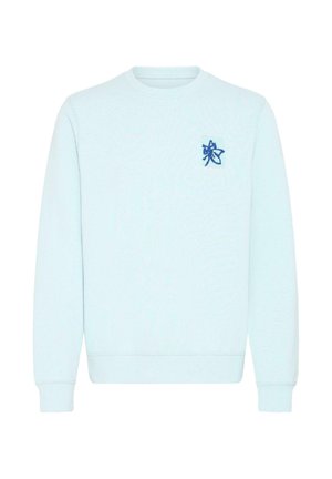 Lys blå genser laget av mykt stoff, med ribbede mansjetter og nederkant, med en liten blå brodert logo på brystet.