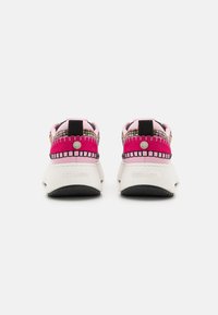 Zapatillas deportivas con una parte superior tejida en rosa y negro, suela blanca y un lazo trasero para ponerlas fácilmente. La marca "Steve Madden" está grabada en el talón.