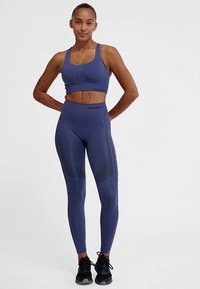 Navyblauw sportset bestaande uit een cropped sportbeha met brede bandjes en een broek met hoge taille met gestructureerde zijpanelen en bijpassende accenten.