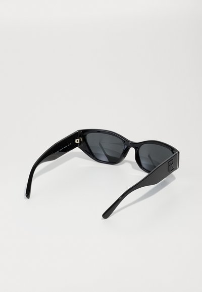 Schwarze Sonnenbrille mit glänzender Oberfläche, kantiger Katzenaugenform, getönten Gläsern und breiten Bügeln mit eingeprägtem Logo.