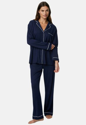 Navy cotton pajama set with white piping. Includes button-up long-sleeve top with pocket and matching wide-leg pants. Soft texture.