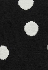 Melna vannas istabas paklājiņš ar baltām apļveida rakstu zīmēm ar dažādu izmēru faktūrām, kas skaidri kontrastē ar tumšāku fonu.