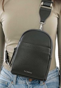 Černá kožená crossbody taška s texturovaným povrchem, zipovým uzávěrem a nastavitelným popruhem se stříbrnou sponou. Logo na přední straně.