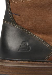 Hnědý semiš s texturovaným vzorem se protíná s hladkou černou kůží. Obsahuje kontrastní švy a logo vyražené na patě.