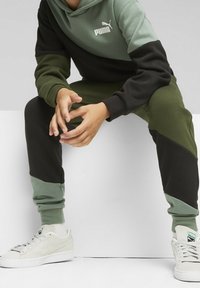 Puma hoodie en joggers in groen en zwart kleurblokontwerp. Hoodie heeft een kangaroo pocket, joggers hebben elastische boorden en een trekkoord.