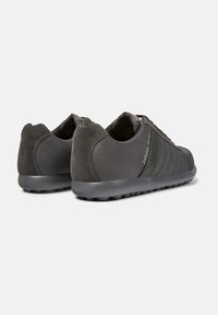 Dark grey athletic shoes with a smooth synthetic upper and suede accents. Features a textured rubber sole and minimalistic design.
