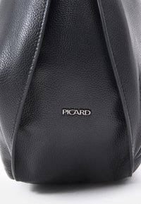 Czarna torebka ze strukturalną formą, wykonana z teksturowanej skóry, z gładkimi krawędziami i srebrnym logo "PICARD" z przodu.