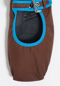 Zapato de tela marrón con ribete azul y una correa con hebilla plateada, que presenta una plantilla negra texturizada, aislado sobre un fondo blanco.