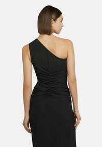 Schwarzes Kleid mit einem Schulterträger, das Raffung am Rücken aufweist, eine glatte Textur hat und eine figurbetonte Silhouette bietet. Keine zusätzlichen Verzierungen.