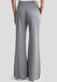 Pantalons larges gris clair avec une texture lisse, un design ajusté et une taille mi-haute. Comprend deux poches arrière.