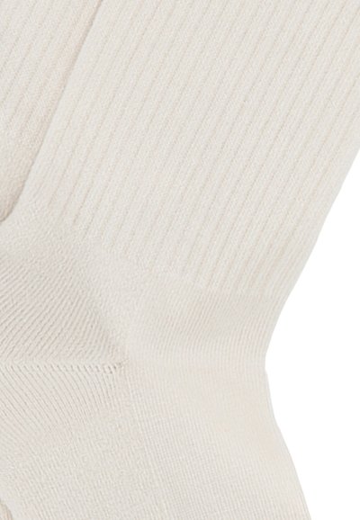 Calzino a coste color crema con superficie texturizzata, caratterizzato da un design elasticizzato e un tallone rinforzato per una maggiore durata.