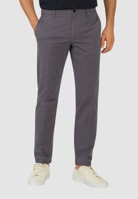 Pantaloni grigi realizzati in tessuto leggero, con un design a gamba dritta, tasche frontali e chiusura con bottone. Indossati con sneakers bianche.