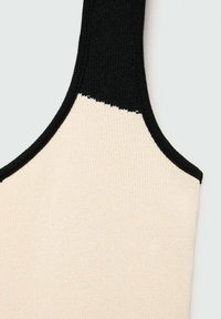 Canotta a coste con corpo crema e scollo nero. Il design presenta un blocco di colore nella parte superiore con una texture liscia.