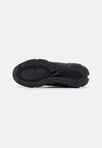 Semelle de chaussure en caoutchouc noir avec motif de bande de roulement texturé, comprenant des rainures et un design incurvé pour l'adhérence. Aucun logo ou accent visible.