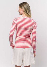 Pikad varrukad, kitsa lõikega särk vahelduvate korallroosade ja valgete triipudega. Valmistatud soonikkoest, millel on ümara kaelusega, kitsad varrukad ja õrnalt vormitud lõige.