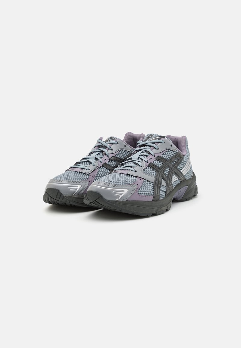 Sportieve schoenen met een bovenwerk van mesh in grijs en lavendel, met een gevoerde zool, vetersluiting en een textuurpatroon op de zijkanten.