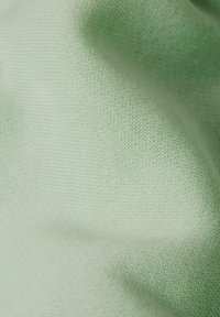 Texture de tissu vert clair avec une surface douce et lisse et un motif tricoté, affichant de petites coutures régulières partout.