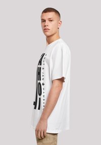 White cotton t-shirt featuring a bold black graphic print on the front. The design includes the text "Knut & Jan Hamburg" vertically along the side.