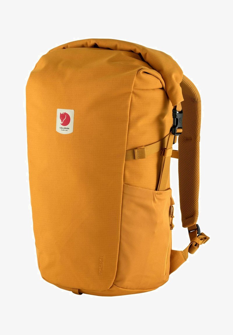 Pomarańczowy plecak z rolowanym zamknięciem, wykonany z wytrzymałego materiału, z regulowanymi paskami, siateczkowym panelem z tyłu i boczną kieszenią dla łatwego dostępu.