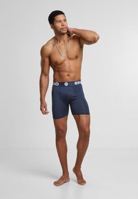 Boxers bleu marine en tissu extensible avec un waistband de marque. Design ajusté avec une texture lisse et sans motifs visibles.