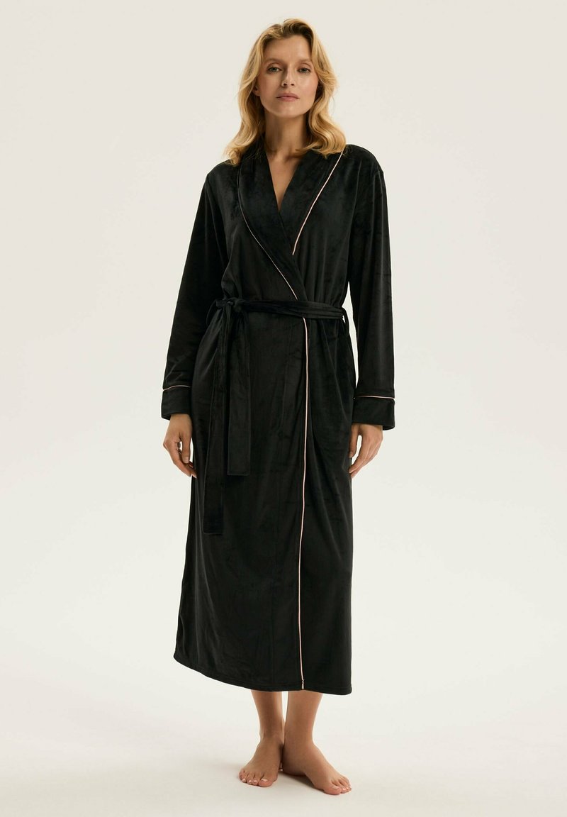 Czarna szata z miękkiego materiału welurowego, z kołnierzem szalowym, długimi rękawami, pasa w talii i kontrastowym jasnoróżowym wykończeniem wzdłuż brzegów.