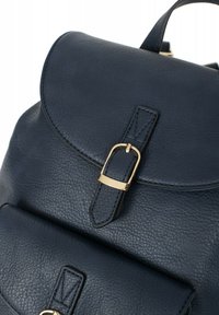 Granatowy skórzany plecak z zaokrąglonym klapą, złotymi akcentami i przednią kieszenią. Teksturowane wykończenie z pojedynczym uchwytem u góry.