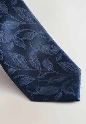 Granatowy krawat z teksturowanym wzorem liści. Wykonany z tkaniny, z plecionym wzorem w ciemniejszym odcieniu, zwężanym końcem i klasycznym kształtem.