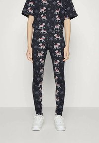 Leggings pretos com um padrão de inverno apresentando cães vermelhos e brancos e flocos de neve. Feitas de um tecido elástico, desenhadas para conforto.