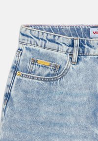 Pantalones cortos de mezclilla azul clara con una cintura estándar, un pequeño bolsillo delantero y una etiqueta de marca dorada. Presenta una tela texturizada y costuras.