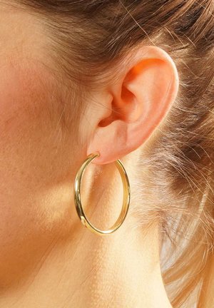 Gold hoop earring featuring a smooth, shiny surface and circular shape, worn on the ear with a close-up view of the design and texture.