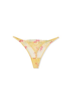 String en dentelle jaune transparente avec broderie florale en rose, blanc et vert, avec fines bretelles latérales sur fond blanc.
