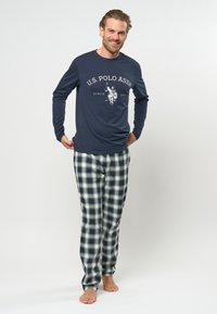 Marine lange mouw shirt met het logo "U.S. Polo Assn."; groene, marineblauwe en witte geruite pyjamabroek; katoenen stof; losse pasvorm; zachte textuur.