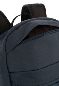 Dunkelblauer Rucksack mit einem Reißverschlussöffnung, strukturiertem Stoff, gepolsterten Trägern und einem verstärkten Handgriff oben.