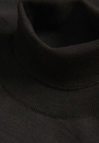 Sort pullover med høj hals og ribbet tekstur. Designet er tætsiddende, og stoffet er glat.