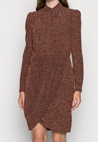Robe à manches longues dans un motif texturé marron et orange, avec un col haut et un design enveloppant avec des fronces à la taille.