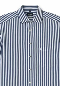 Maglietta a righe con strisce verticali blu navy e bianche, con chiusura a bottoni sul davanti, colletto classico e una tasca sul petto. Il tessuto sembra morbido.