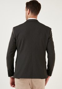 Blazer da uomo grigio scuro; tessuto texturizzato, vestibilità su misura, spacco singolo sul retro, rever a punta e polsini con bottone.