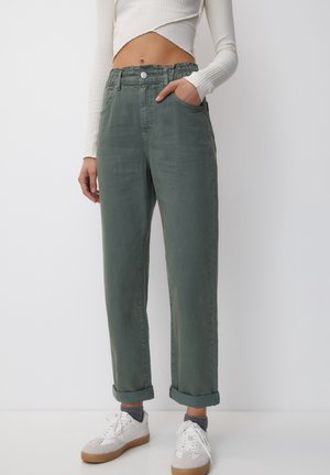 Lichtgroene, relaxed-fit broek met een elastische tailleband en opgerolde manchetten. De stof lijkt zacht met een licht gestructureerde afwerking.