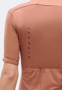 Κοντινό πλάνο στην πλάτη ενός ατόμου που φοράει κοντομάνικο υφασμάτινο καφέ-ροζ ποδηλατικό μπλουζάκι με τρεις πίσω τσέπες και λογότυπο "Pogodone".