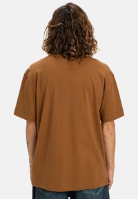 Braunes Baumwoll-T-Shirt mit entspannter Passform, kurzen Ärmeln und rundem Halsausschnitt. Hat eine schlichte Textur ohne sichtbare Muster oder Grafiken.