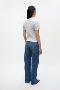 T-shirt grigio a maniche corte aderente abbinato a jeans blue loose-fit. Il tessuto è liscio e con una texture, con un taglio classico e tasche posteriori.