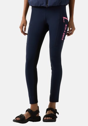 Person wearing navy fitted pants with pink "FIRE + ICE" text on thigh pocket and black open-toe sandals, standing against white background.