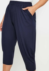 Marina blå cropped byxor i mjukt tyg med elastisk midja och sidofickor. Har en avslappnad passform och insydda fållar.