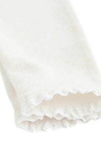 Chaussettes blanches avec bordures en dentelle, en tissu texturé, présentant un motif subtil et des bords froncés, repliées pour afficher l'intérieur.
