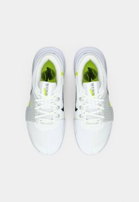 Λευκά αθλητικά παπούτσια με υφασμάτινο επάνω μέρος με υφή, μαύρες λεπτομέρειες και ζωηρά κίτρινα στοιχεία. Περιλαμβάνουν κορδόνια και μαλακή σόλα.