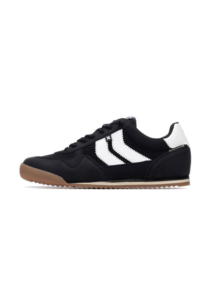 Zapatillas sintéticas negras con tres rayas blancas, suela de goma y un diseño de cordones con un cuello y lengüeta acolchados.